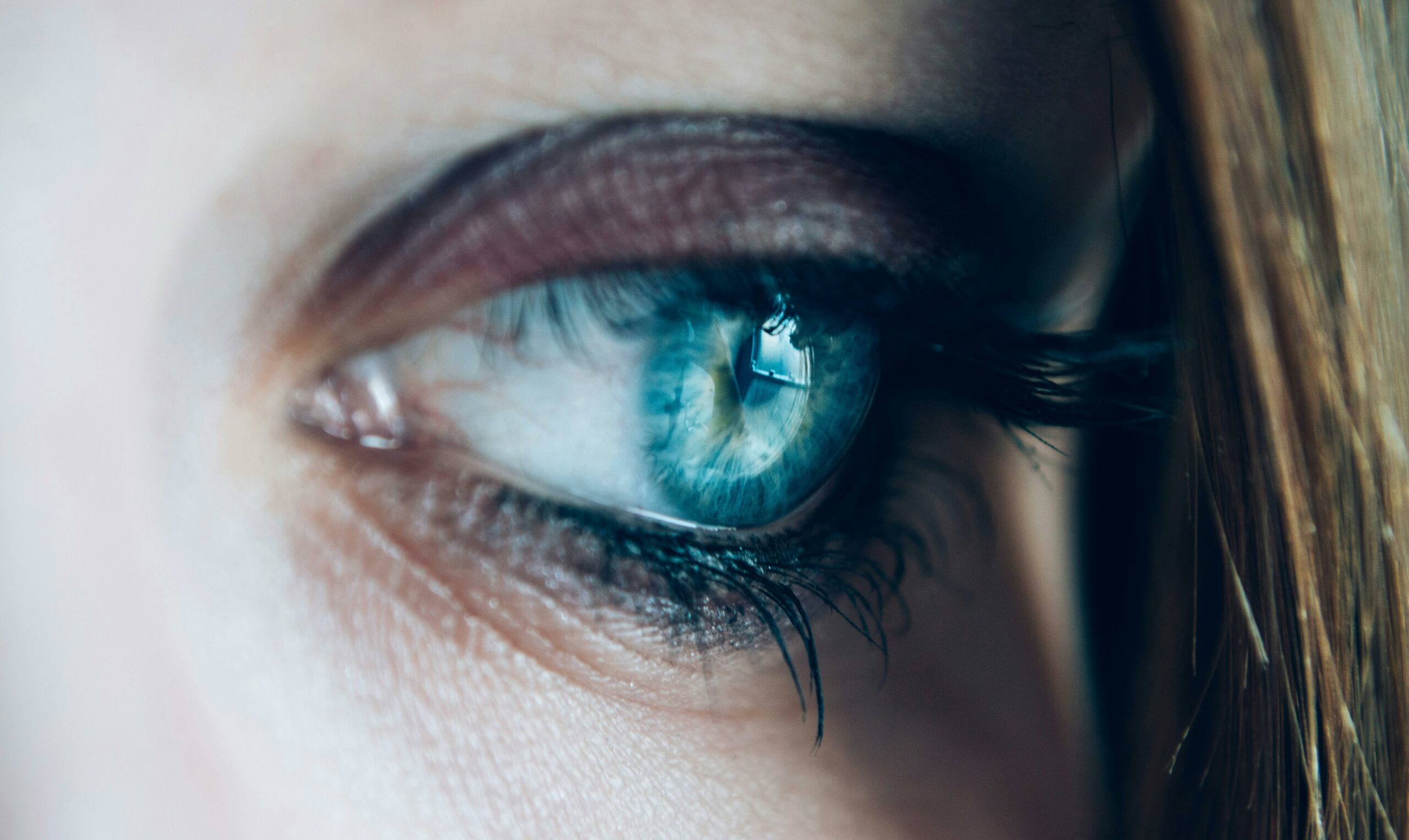 Detailed close-up of a blue eye with long eyelashes, capturing the intricate details of the iris.